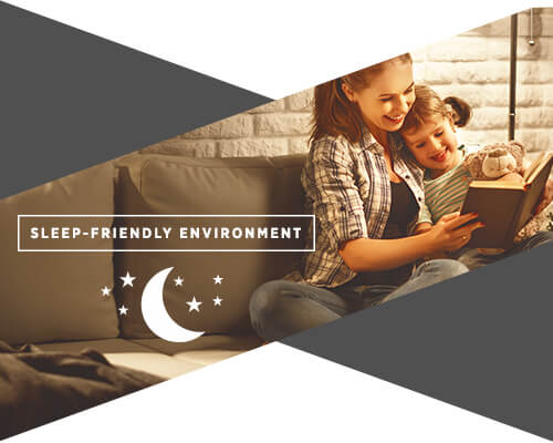 A graphic of a woman and her daughter on a couch reading a book before bed and the text underneath them reads "sleep-friendly environment"